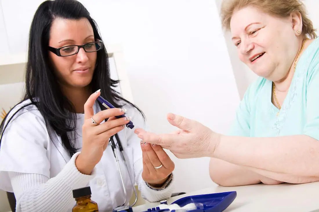 Doctora chequeando nivel de glucosa en persona con diabetes en su fase tardia