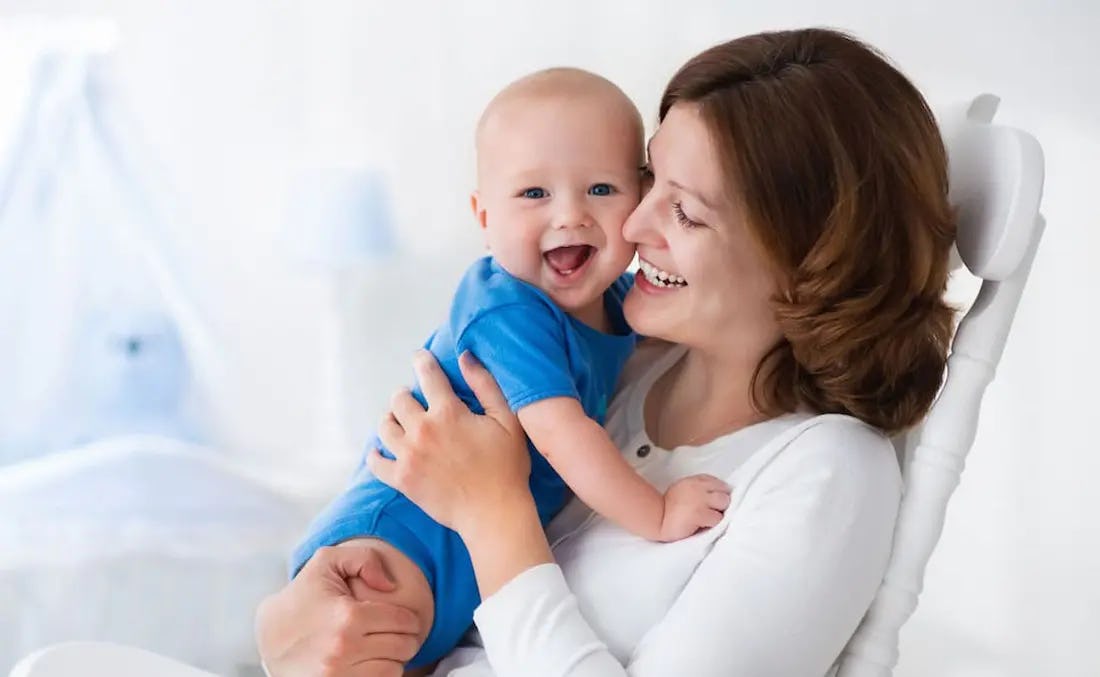 Mujer sonriendo a su bebe sano luego de sufrir de diabetes gestacional