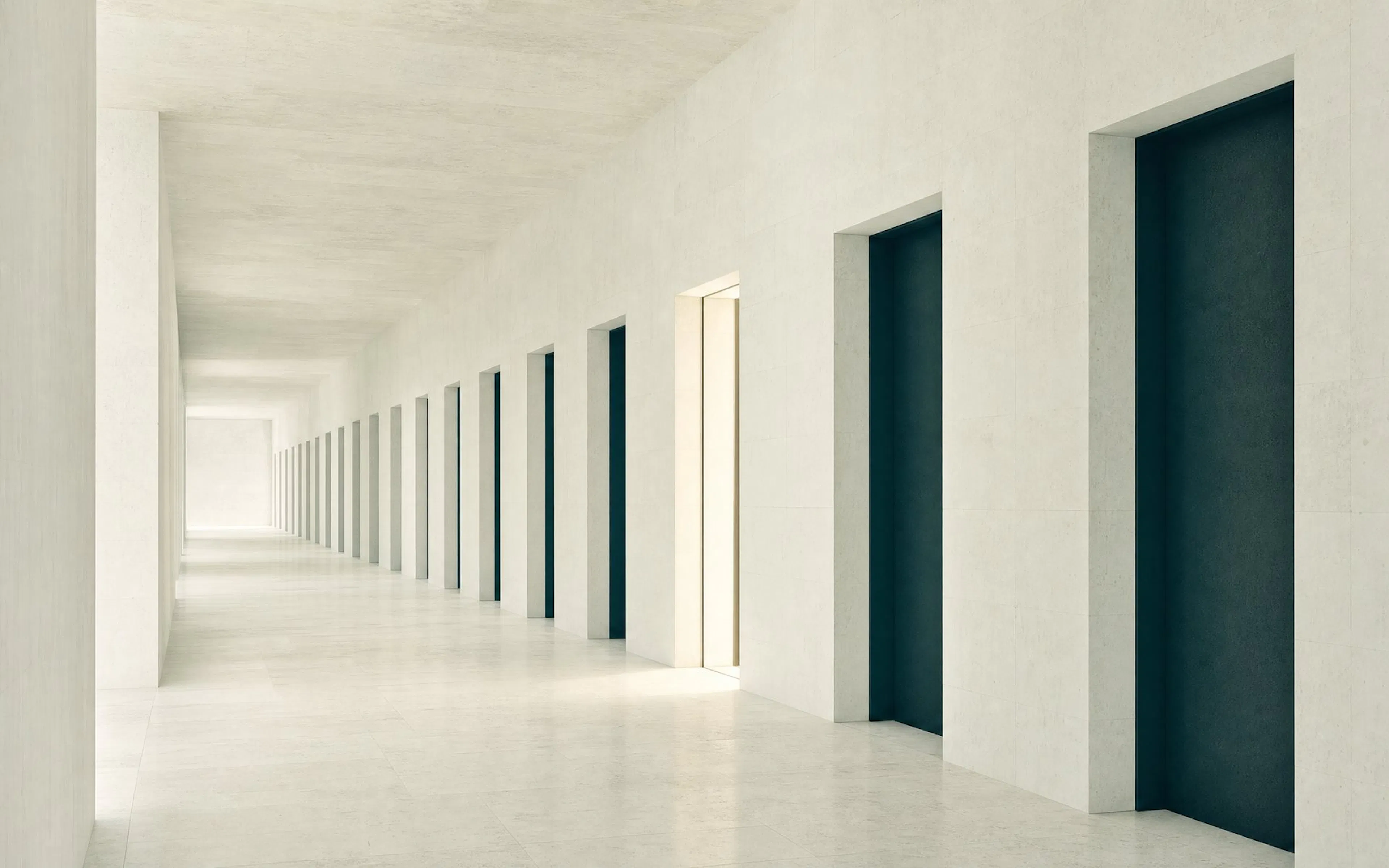 A long limestone corridor of identical closed doorways, with one partway down standing open and lit