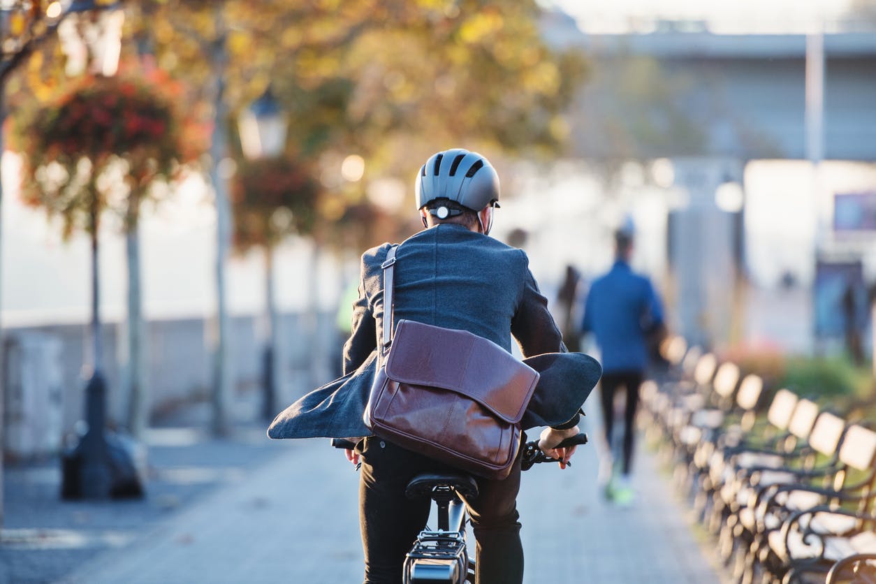 Hombre con una bolsa marrón yendo en bici al trabajo, para reducir su consumo de Co2 