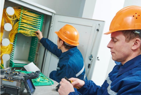 A Bouygues Telecom field technician performing maintenance on a telecommunications cabinet