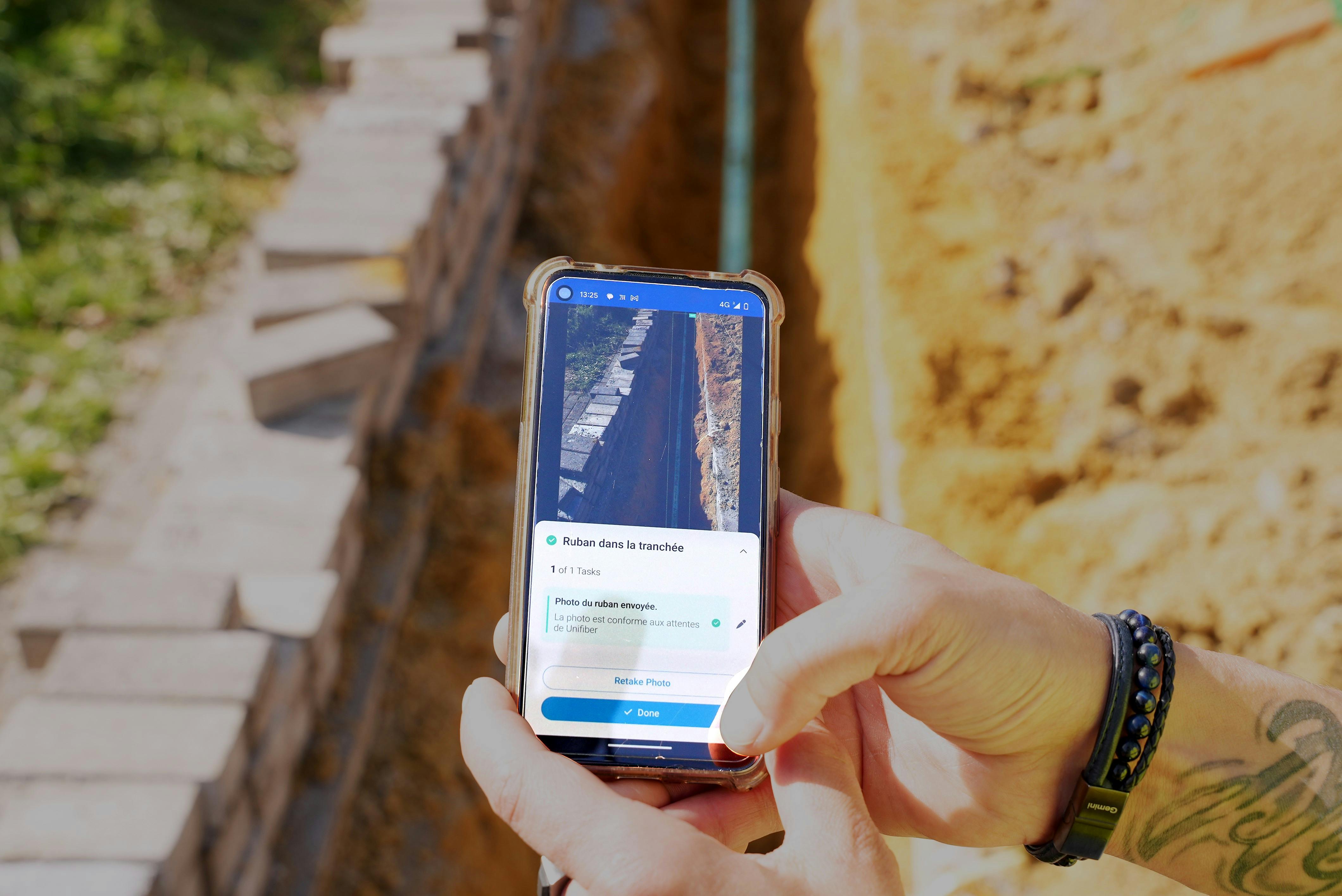 Un technicien fibre d'Unifiber prend une photo d'une tranchée de télécommunication en cours de construction et obtient un retour d'information en temps réel sur son installation.