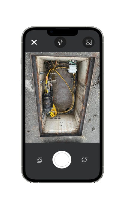 smartphone with a photo of a fiber manhole