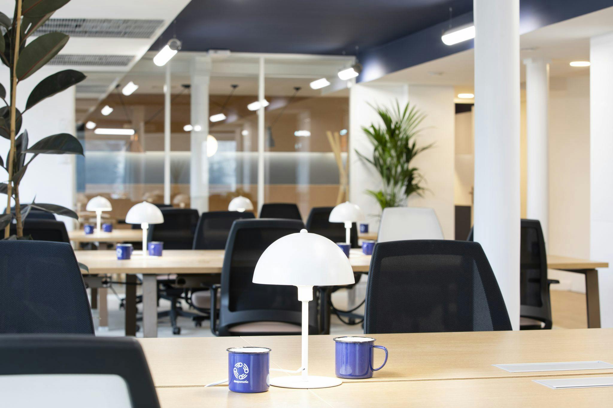 Chaises de bureau noires, tables en bois et colonnes blanches dans le bureau de Deepomatic dans le 3e arrondissement de Paris.