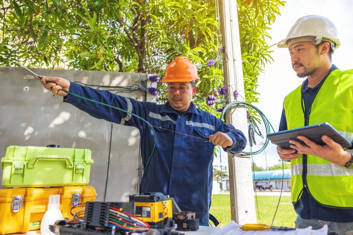 Two field technicians splicing optic fusion cable Internet 

