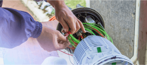 Techniker, der grüne und rote Kabel an einer Glasfaserausrüstung manipuliert 