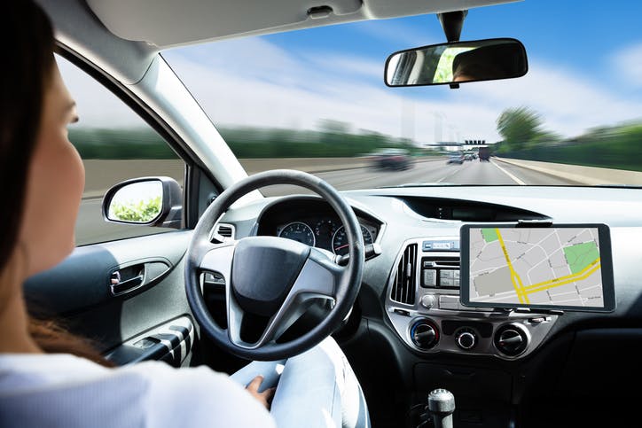 Une femme, les mains entre les jambes, à l'intérieur d'une voiture autopilotée qui circule sur une autoroute.