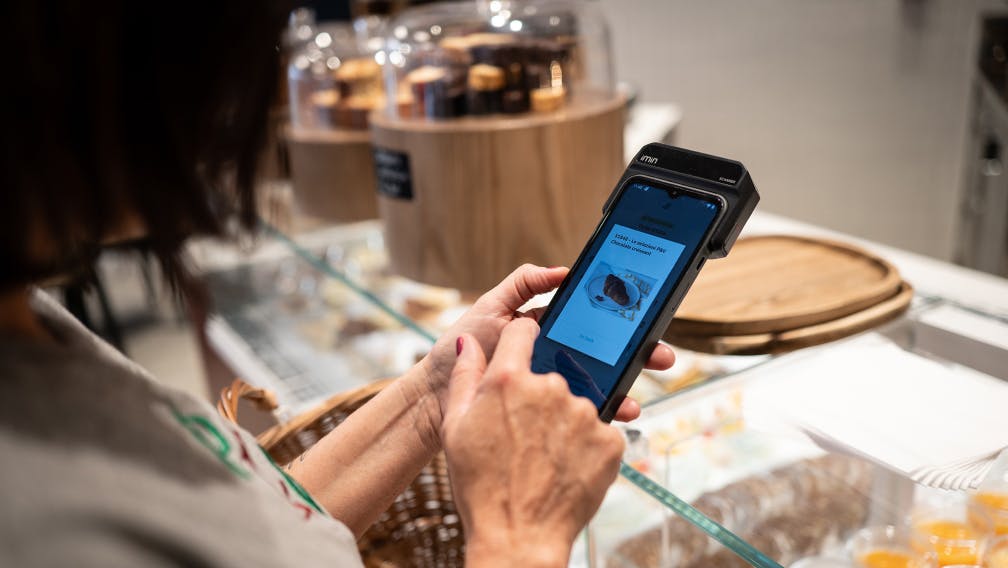 A grocery business owner holding a Deliveroo Order Picker 