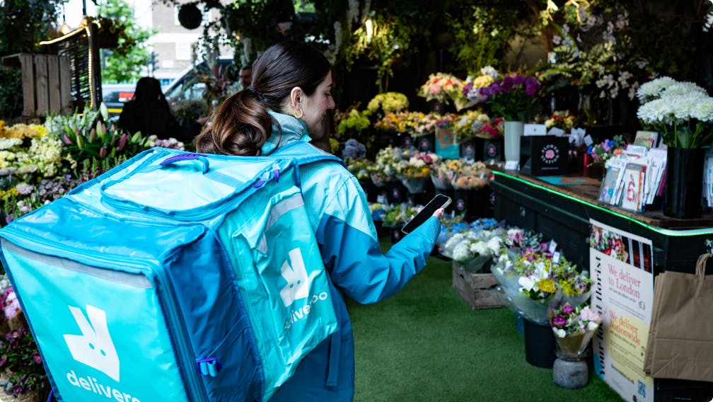 A deliveroo rider in a flower shop