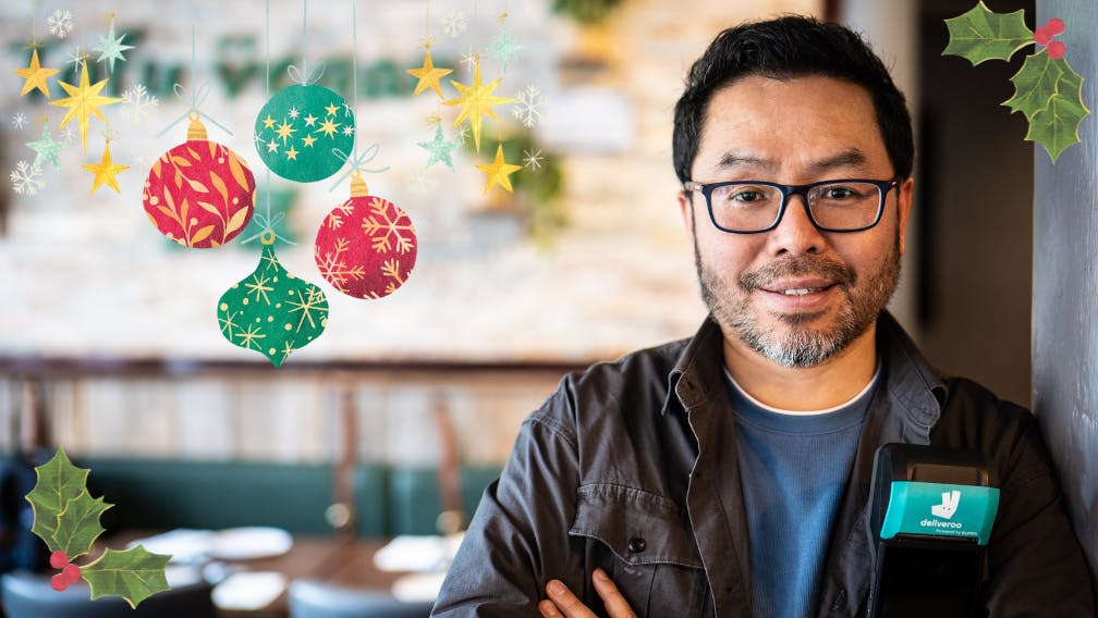 Deliveroo partner holding deliveroo tablet, festive theme