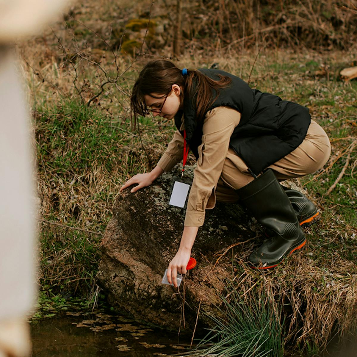 A woman taking a sample from a river.