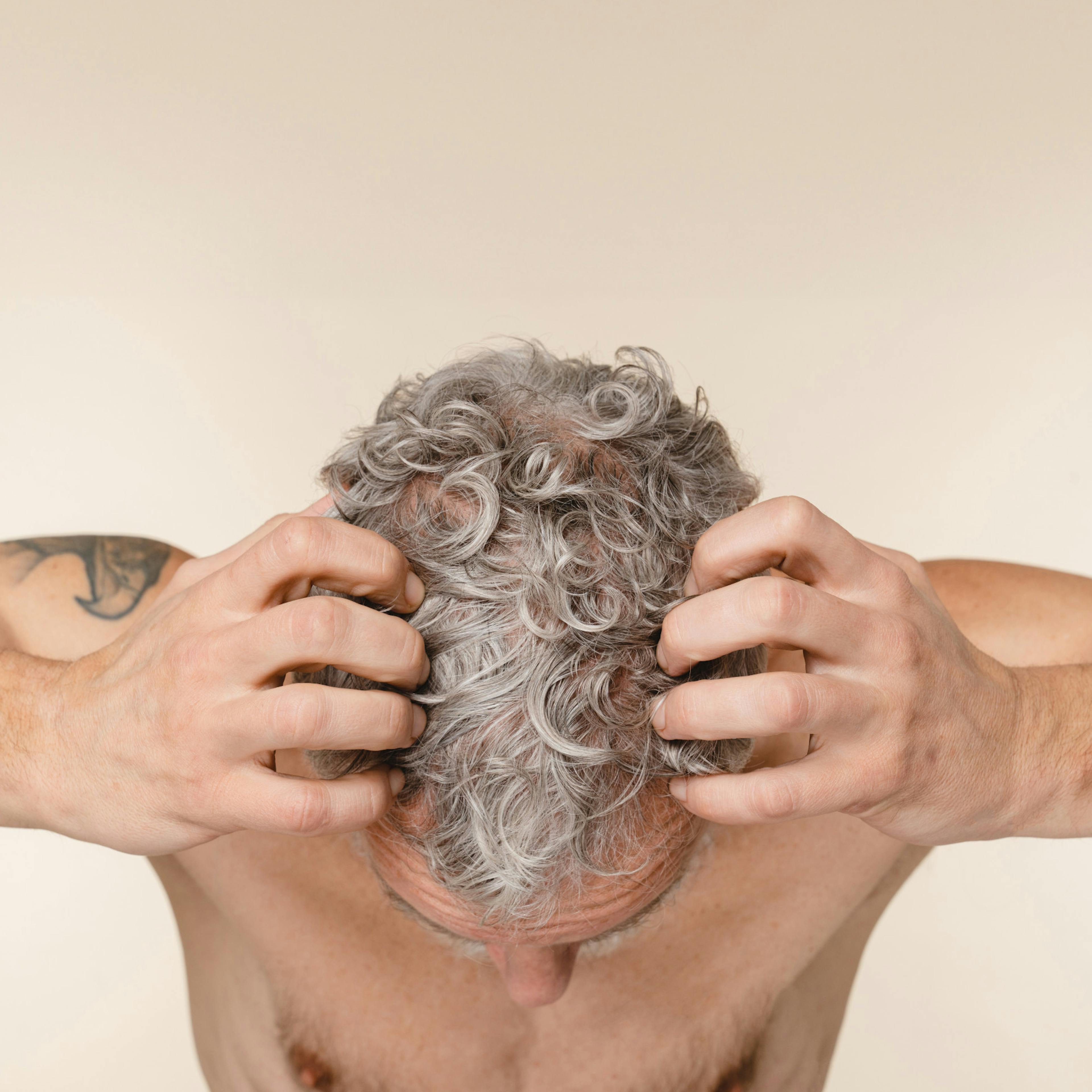 decorative hero image depicting a man with full head of gray hair running his fingers through his hair