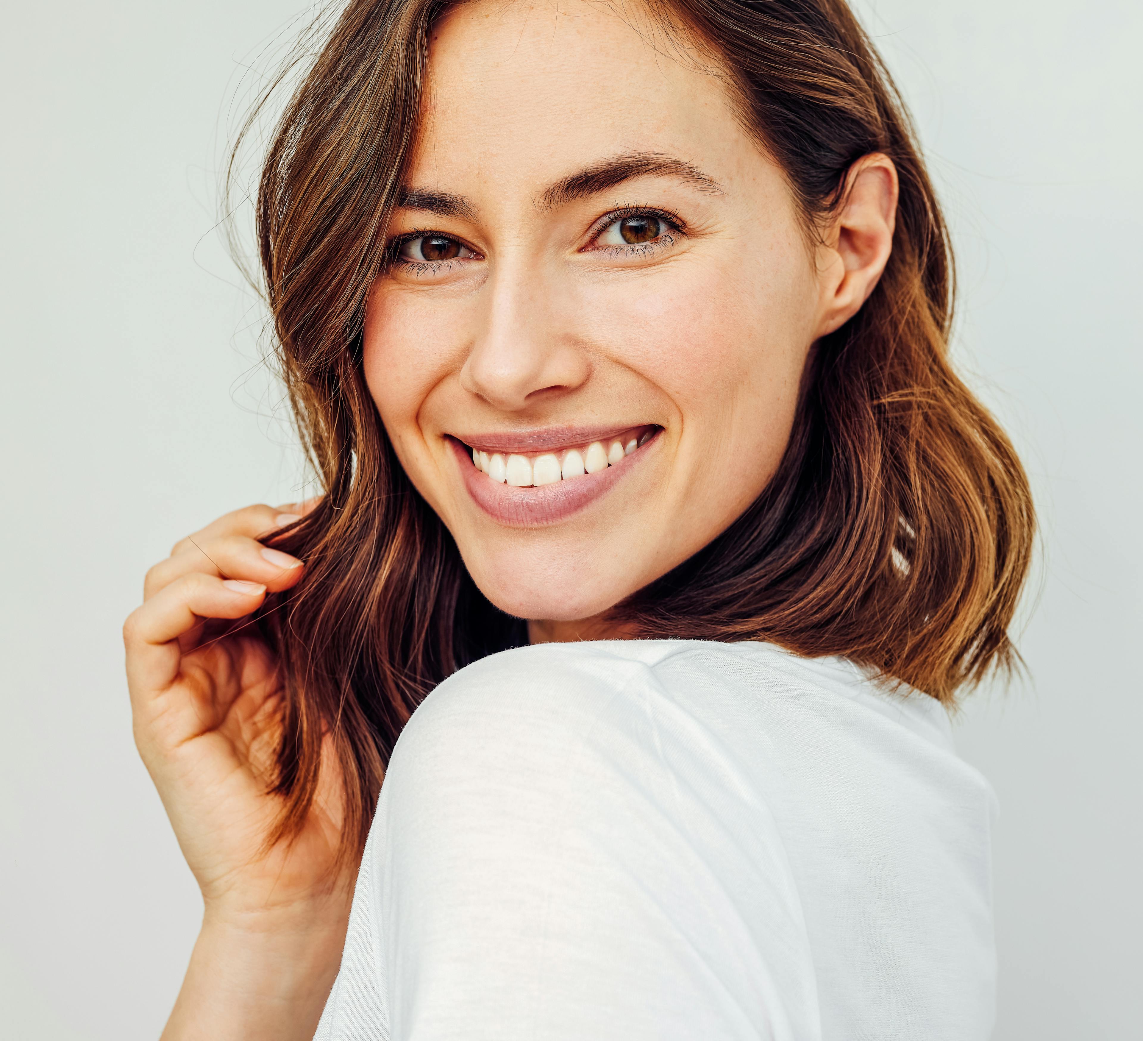 woman with brown hair with clear skin smiling