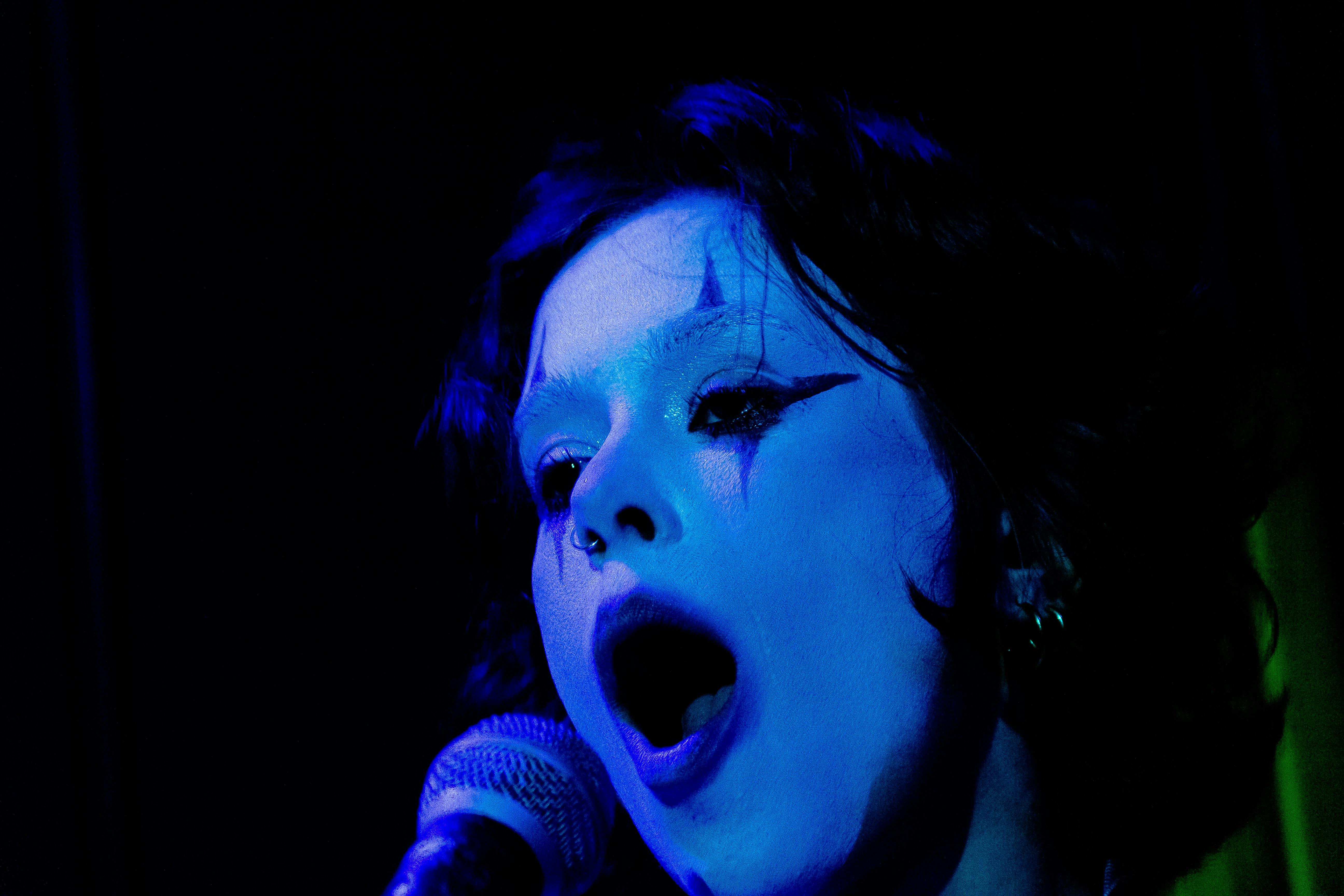 Marina Mole cantando com maquiagem de palhaço.
