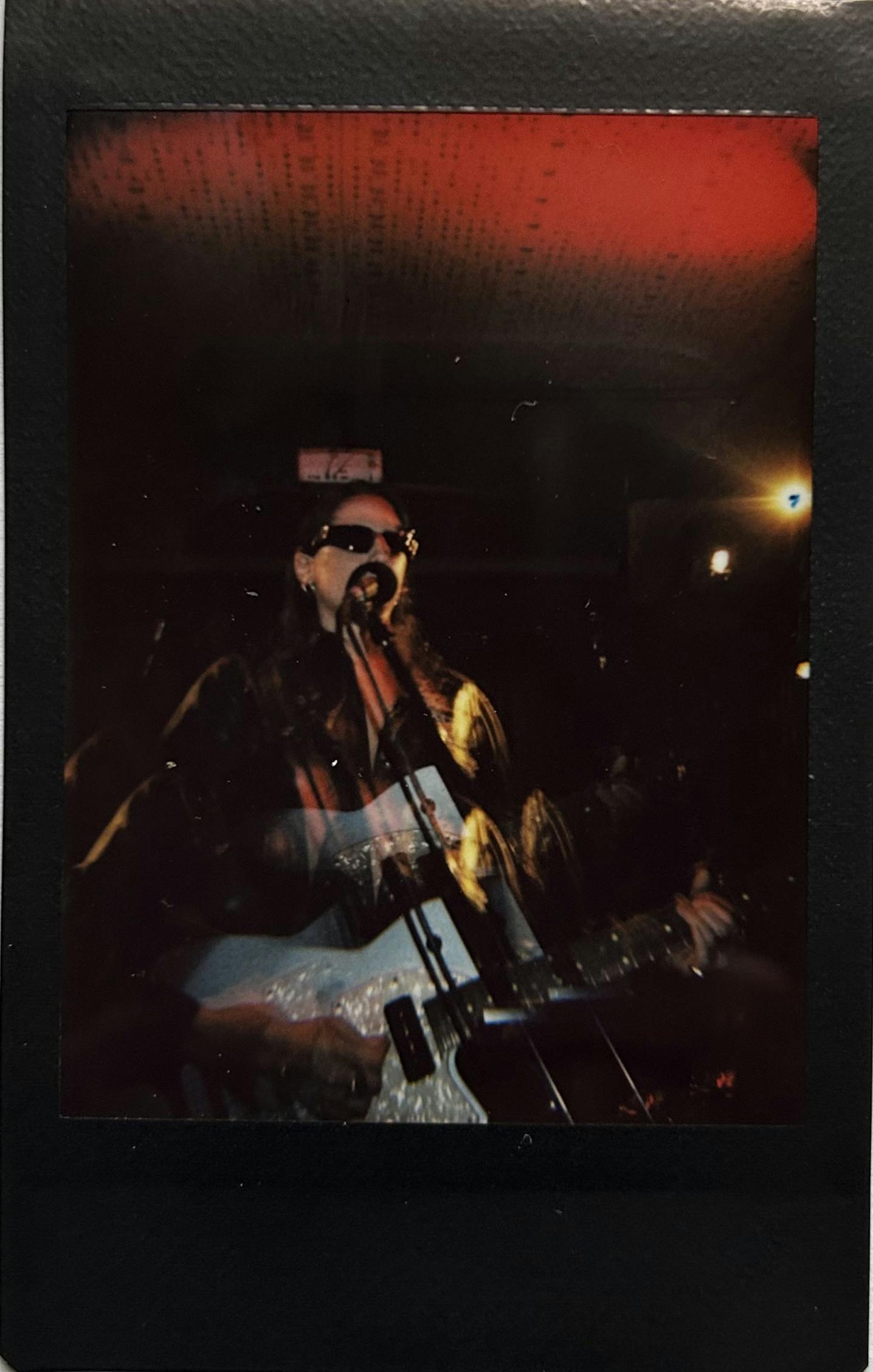 Madre tocando guitarra com um fundo escuro e vermelho