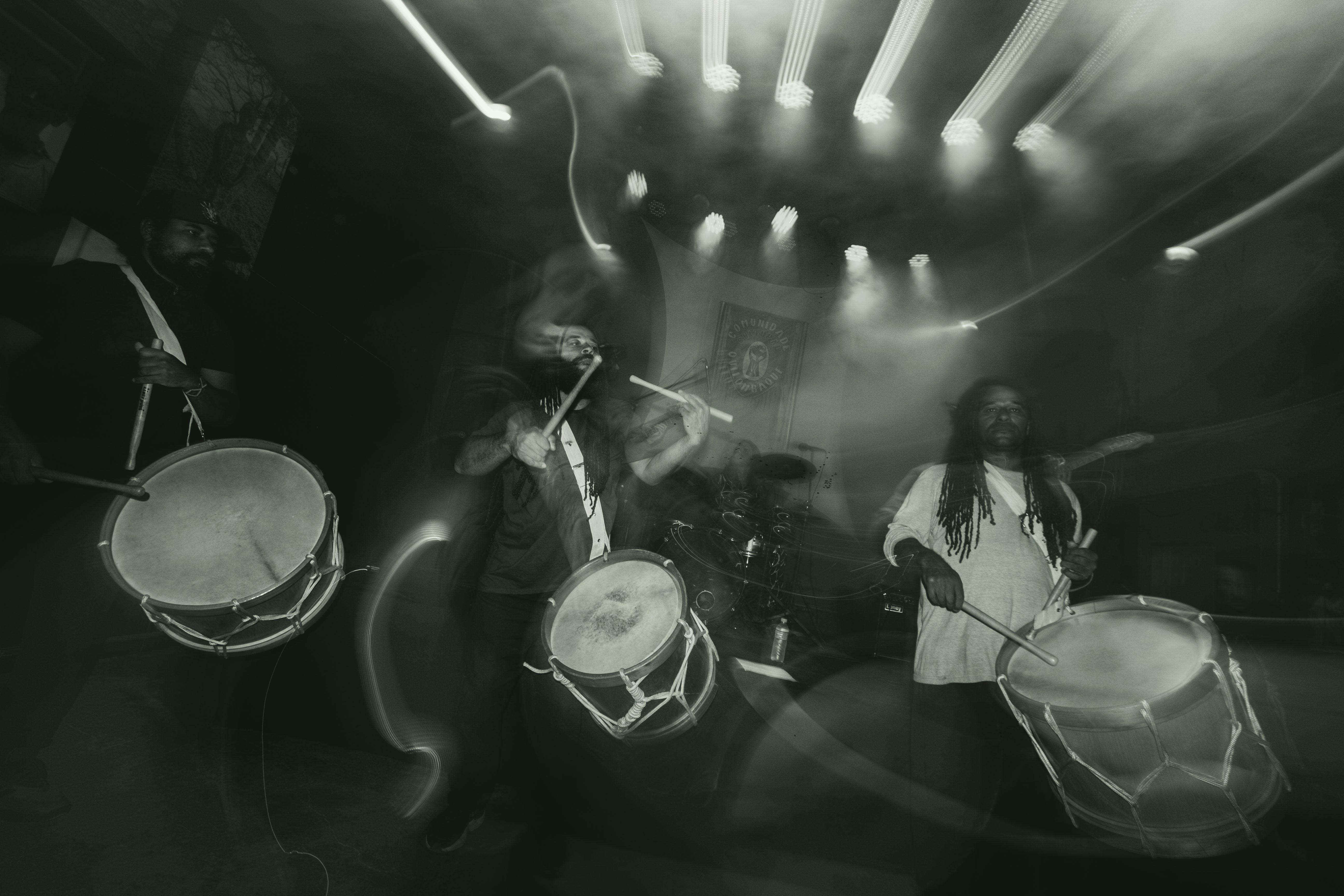 Percussionistas tocam suas alfaias enquanto a banda realiza sua apresentação