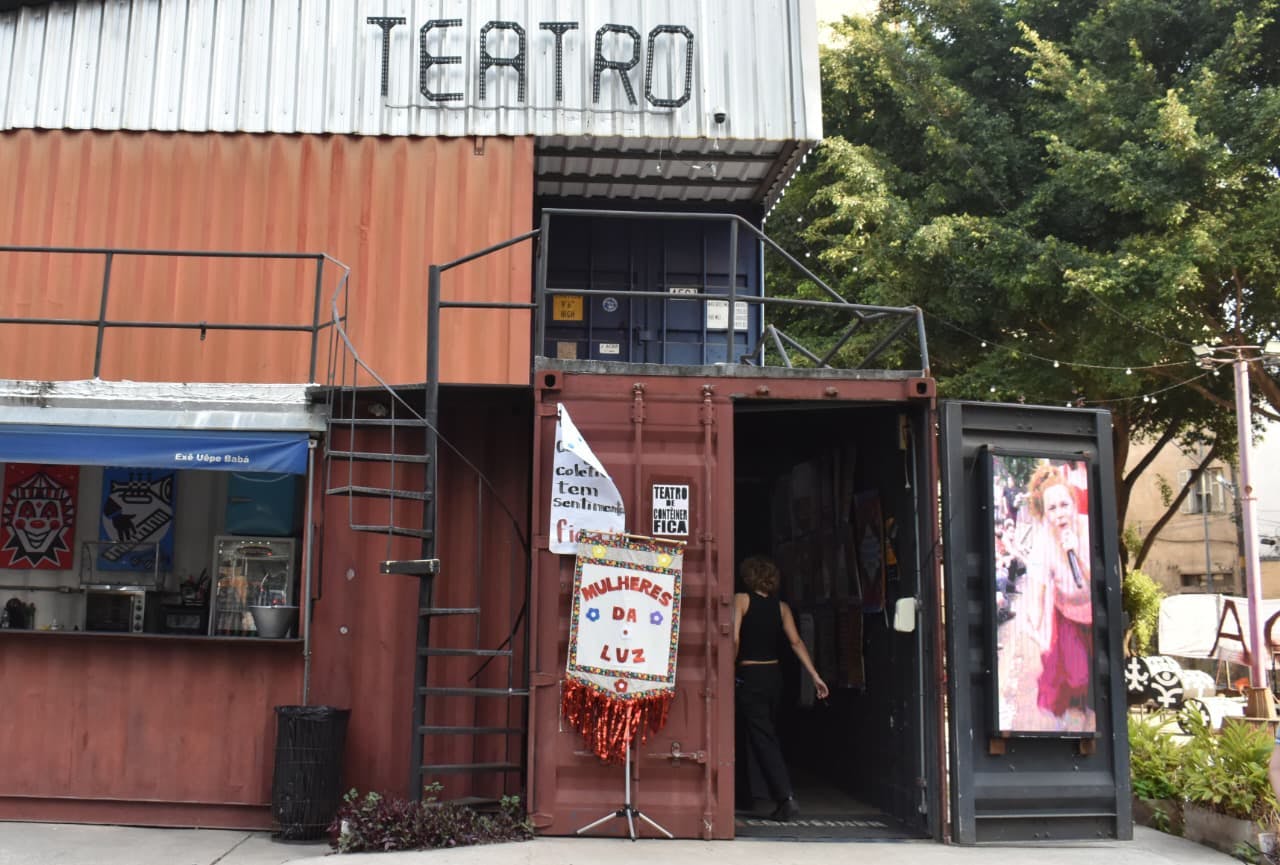 Foto da entrada do teatro de container com a placa das mulheres da luz
