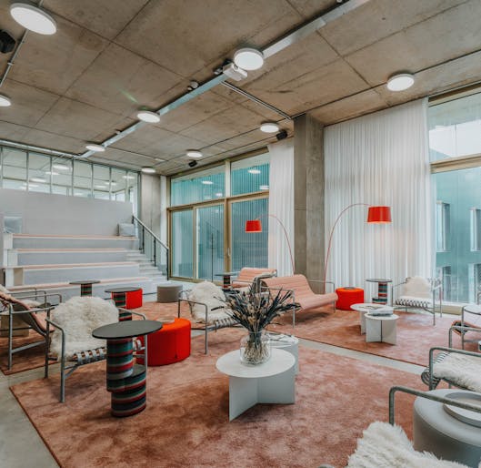 Image of brightly coloured and lit room with red lamps, pink carpet and large windows