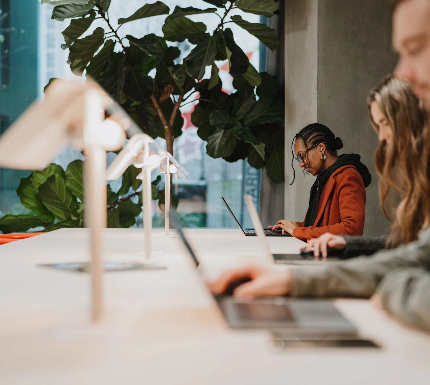 People using laptops at a Coworking desk on a Hot Desk floor.