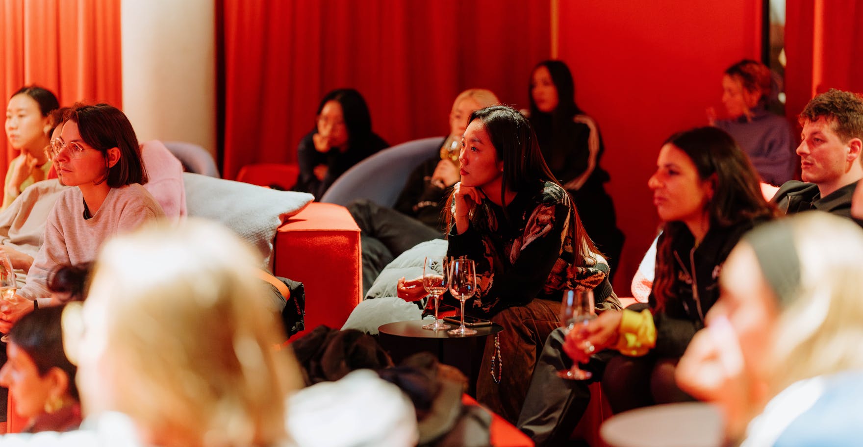 People seated at an event in a red room