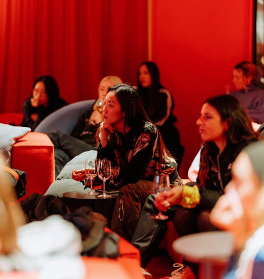 People seated at an event in a red room