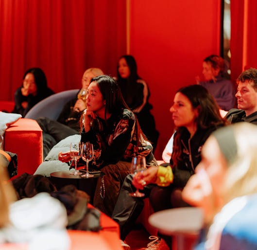 People seated at an event in a red room