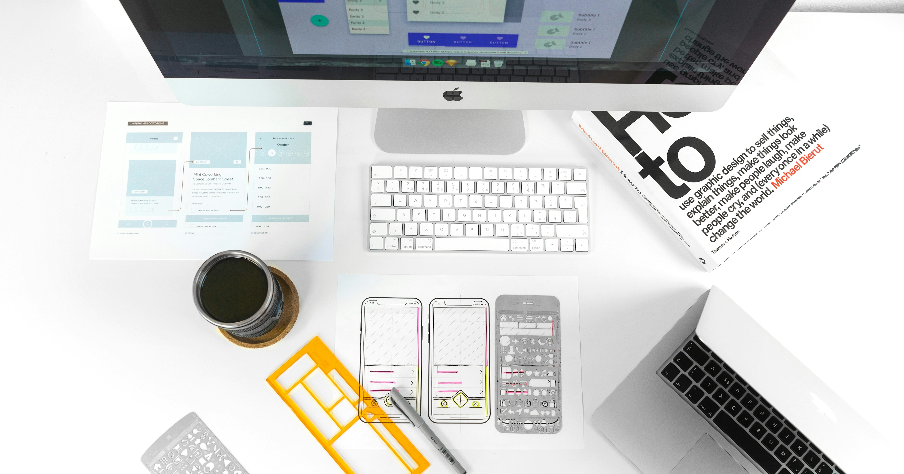 A table with Apple monitor, keyboard and various schematics