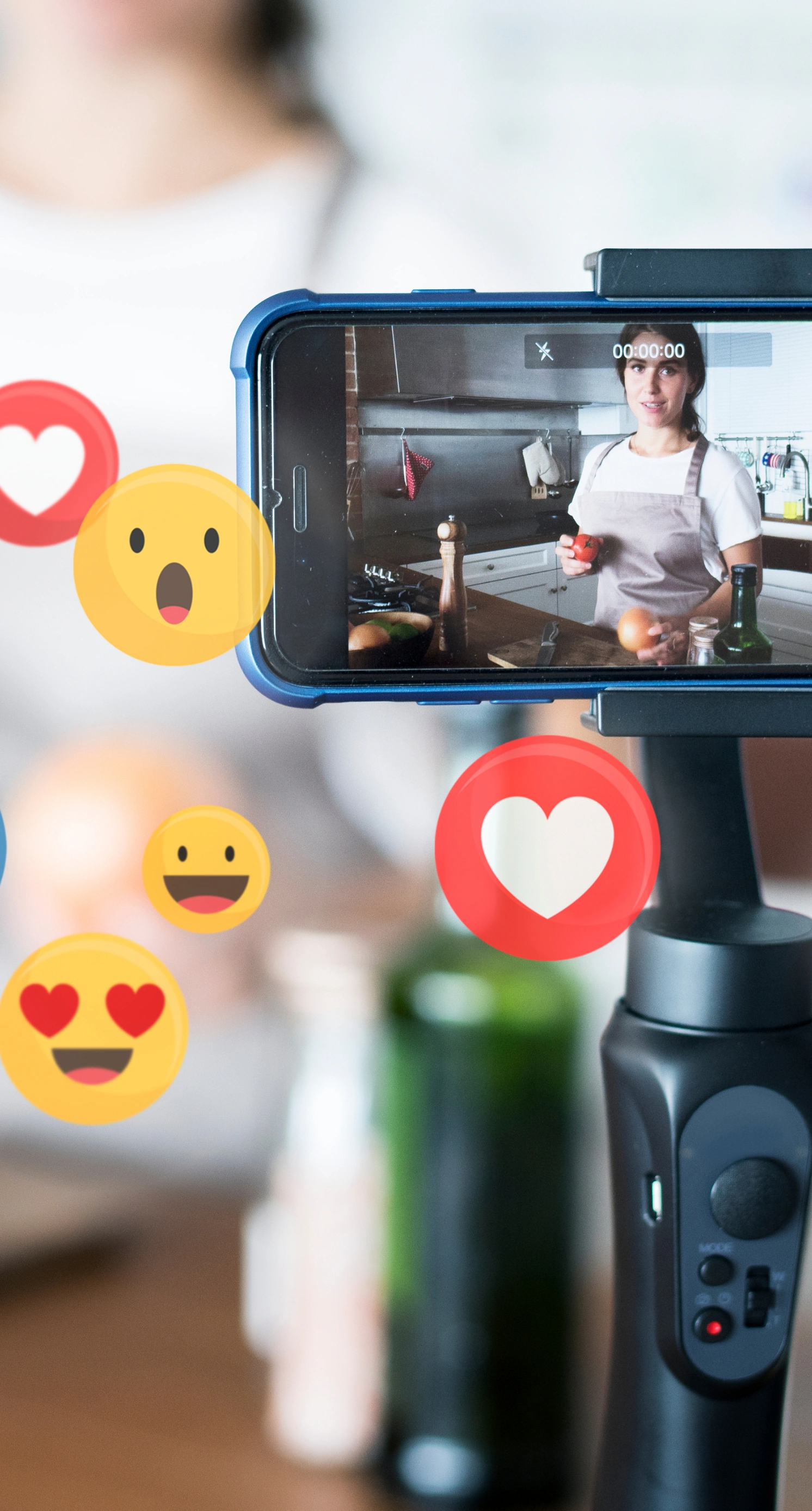 A mobile phone filming video with lots of emojis floating around it