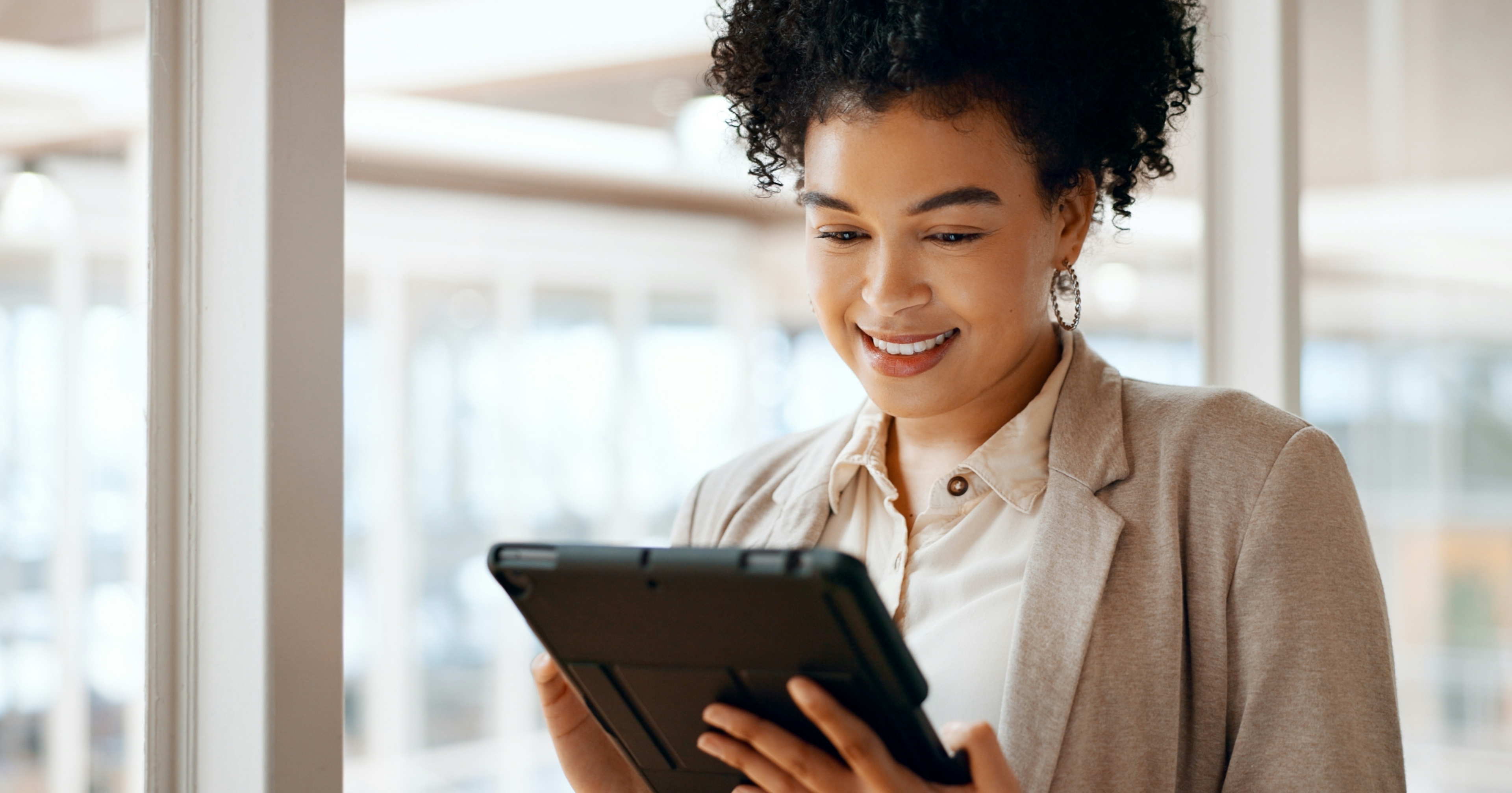 An image of a woman smiling whilst looking at a tablet device