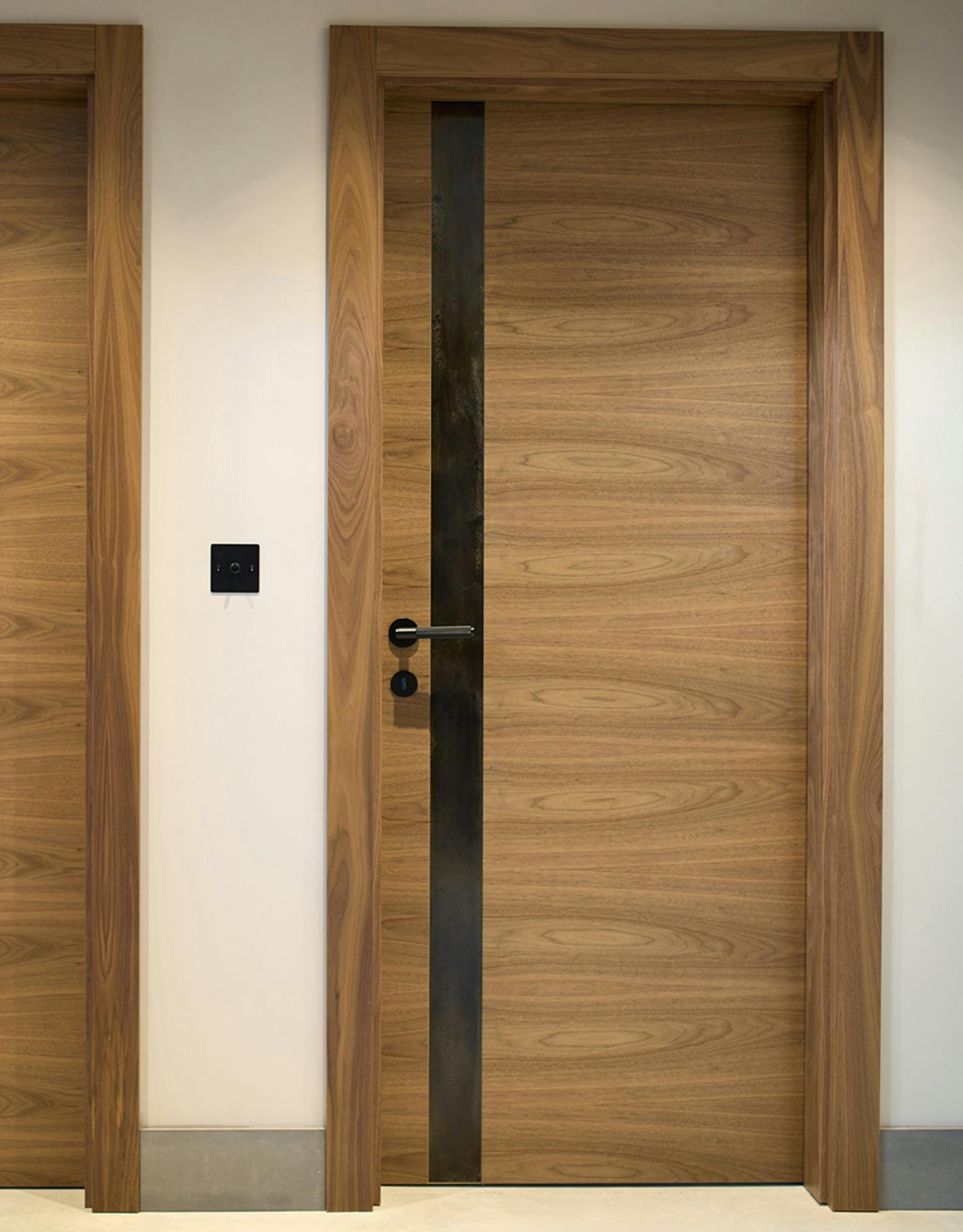 Deuren's bespoke Trem H pocket door in a walnut finish, featuring a vertical metal strip to the left. 