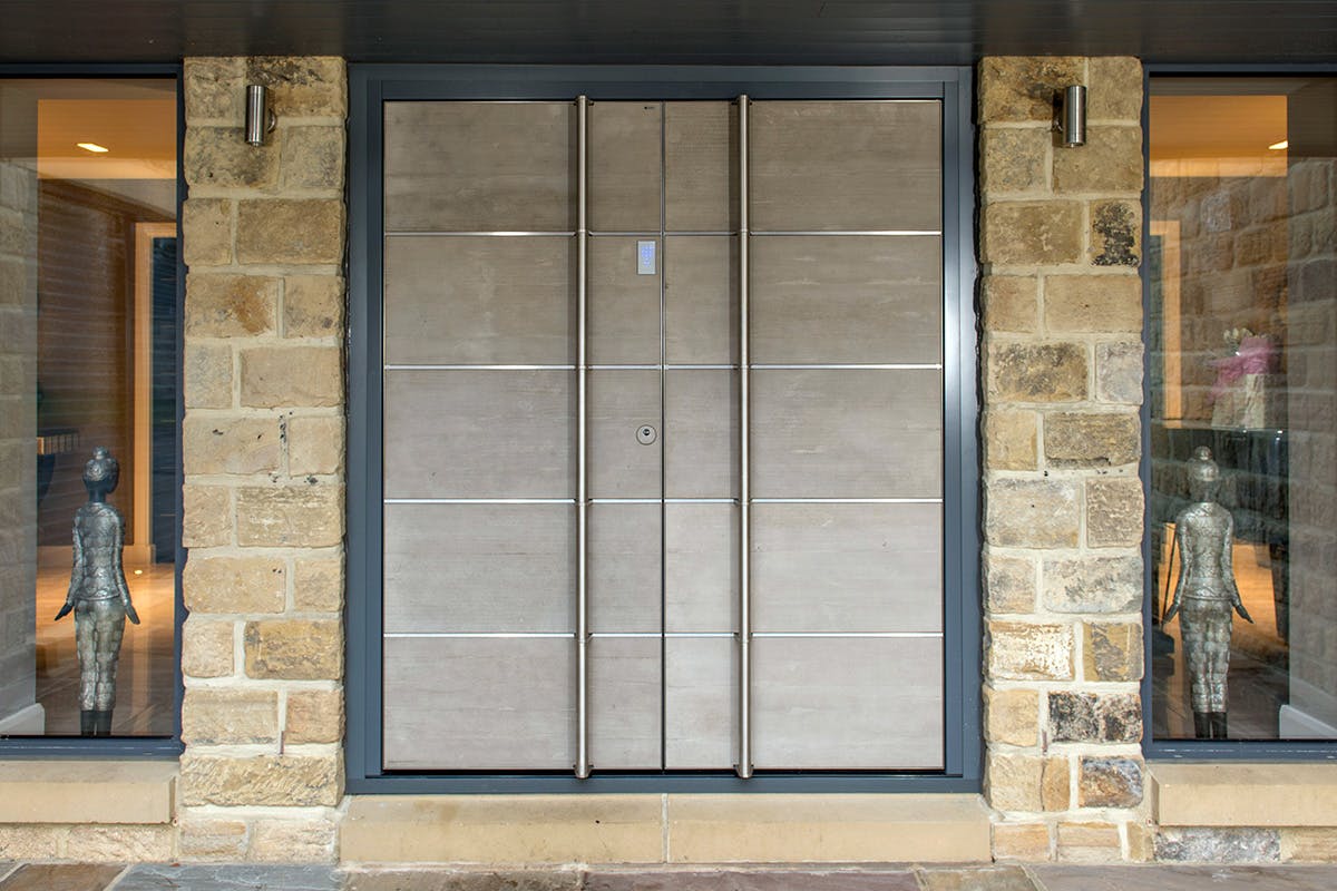 Contemporary light grey concrete look double front doors with long bar handles by Deuren.