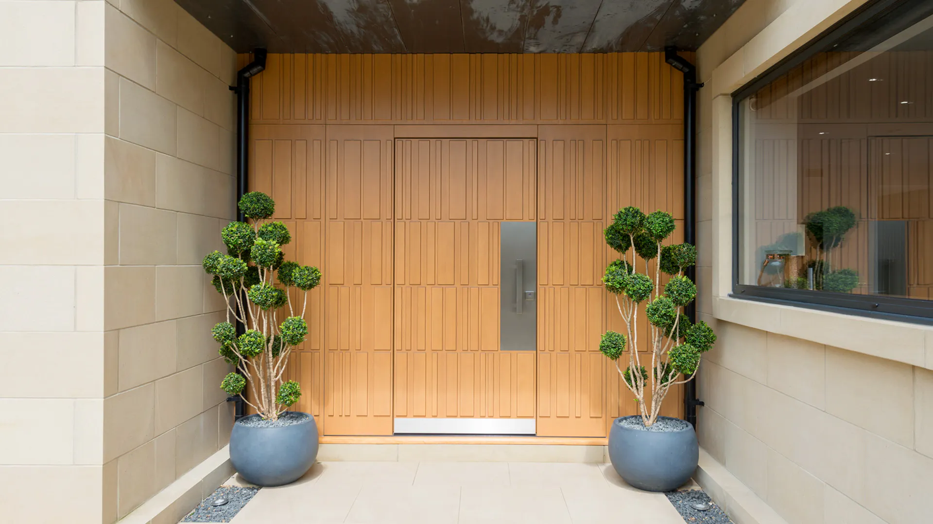 bespoke wooden Tavole front door with two small trees beside