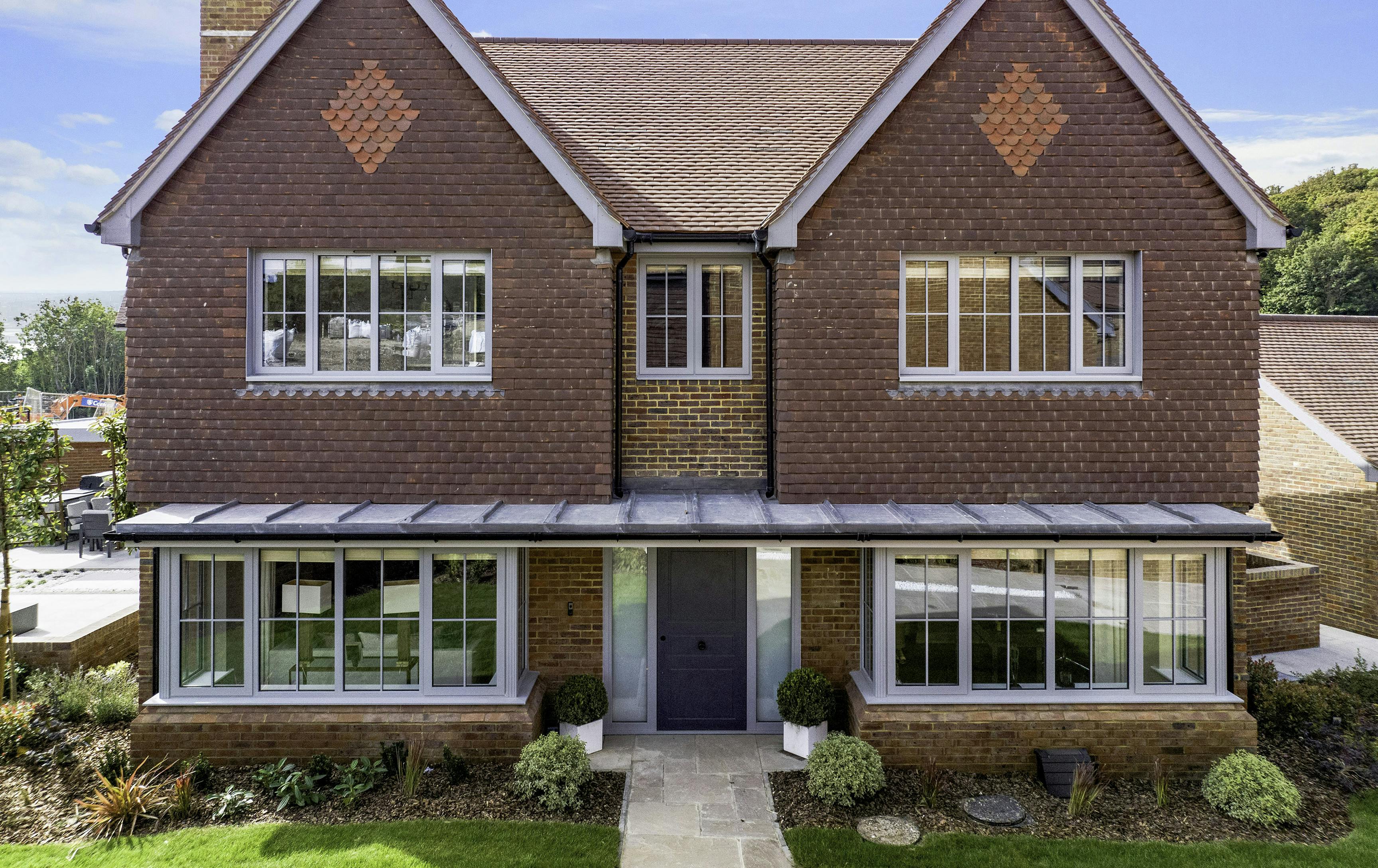 A luxurious double fronted red brick, new build home, featuring a mae-to-measure, Deuren front door in the classic Georgian style, painted drak grey and with two satin glazed side lights.