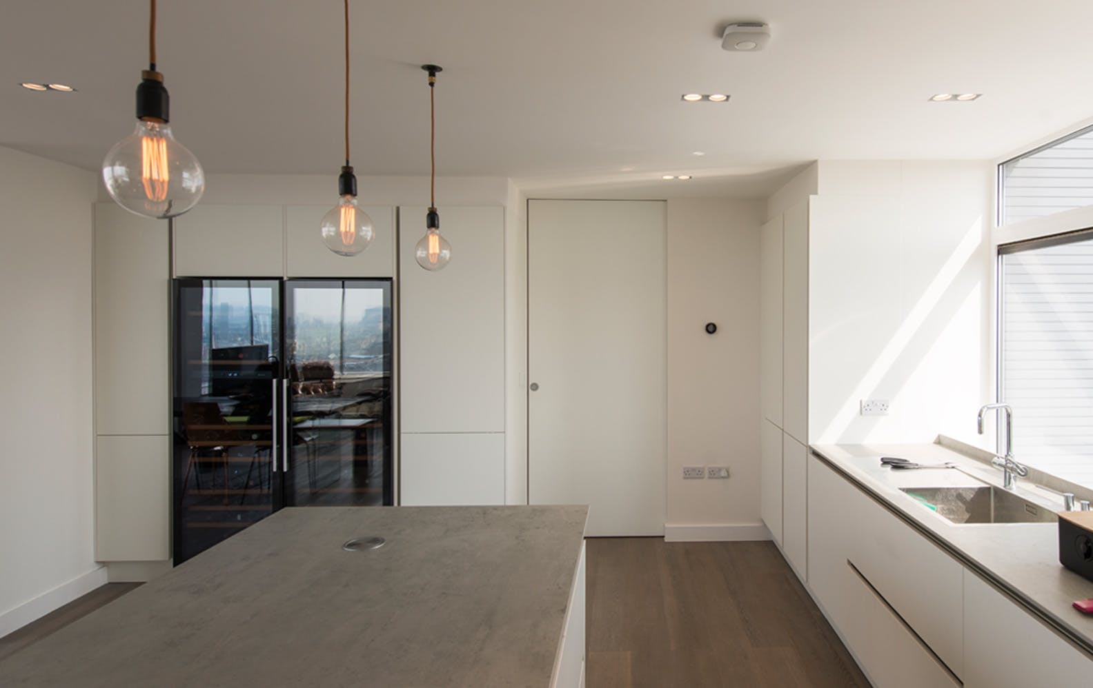 White, contemporary kitchen with a Deuren, full height pocket door - Trem, painted white. Door is closed.