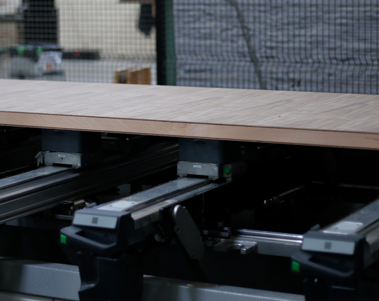 A piece of wood moving along a conveyor belt in a factory.