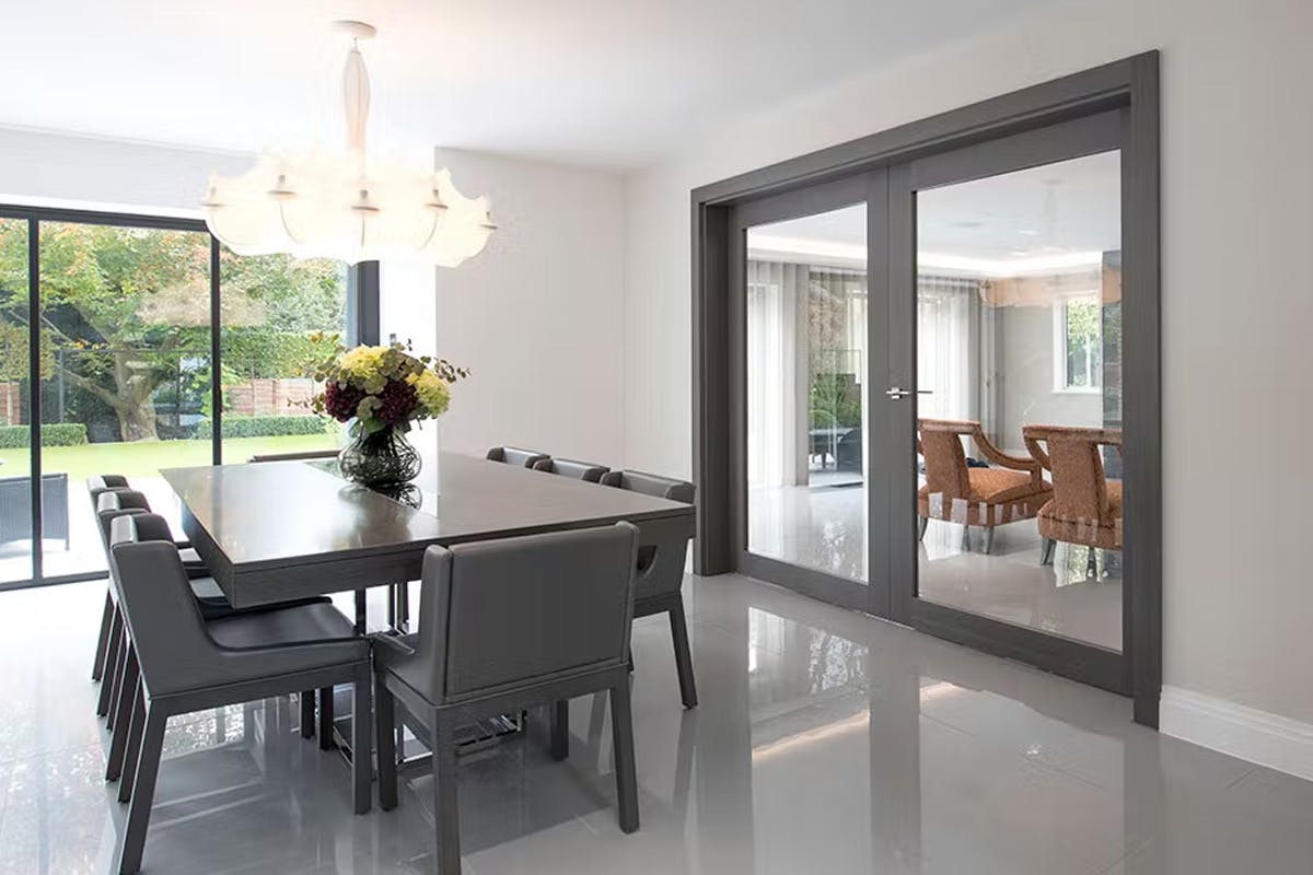 A contemporary dining room with luxury double door set by Deuren - Gio Glass finished in Grey Oak to harmonise with the grey interior.