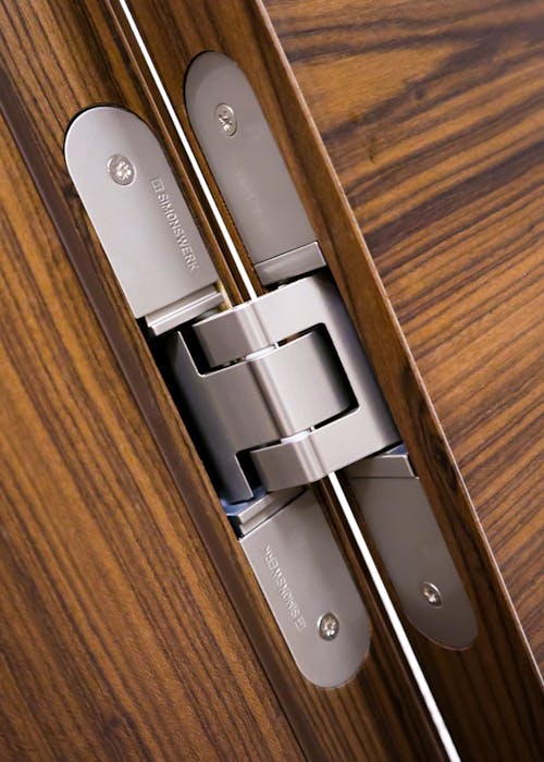 A close up of a hinge on a wooden door.