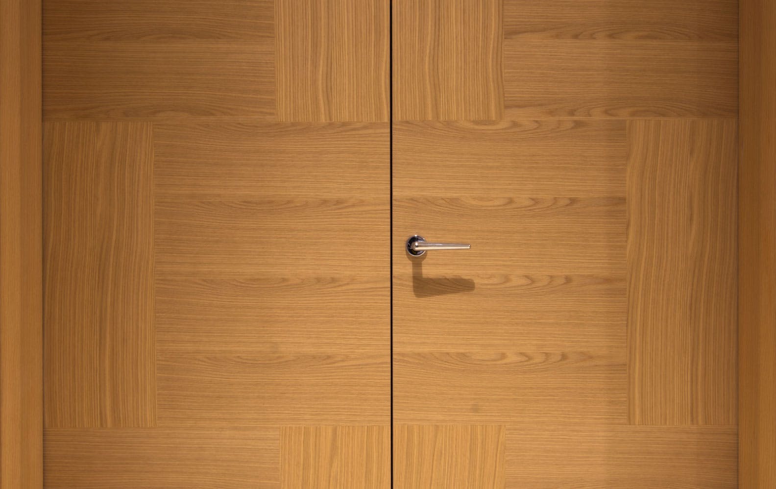 A close up of Deuren double leaf, pre-hung door set - Vario 6 style in natural oak and chrome lever handle