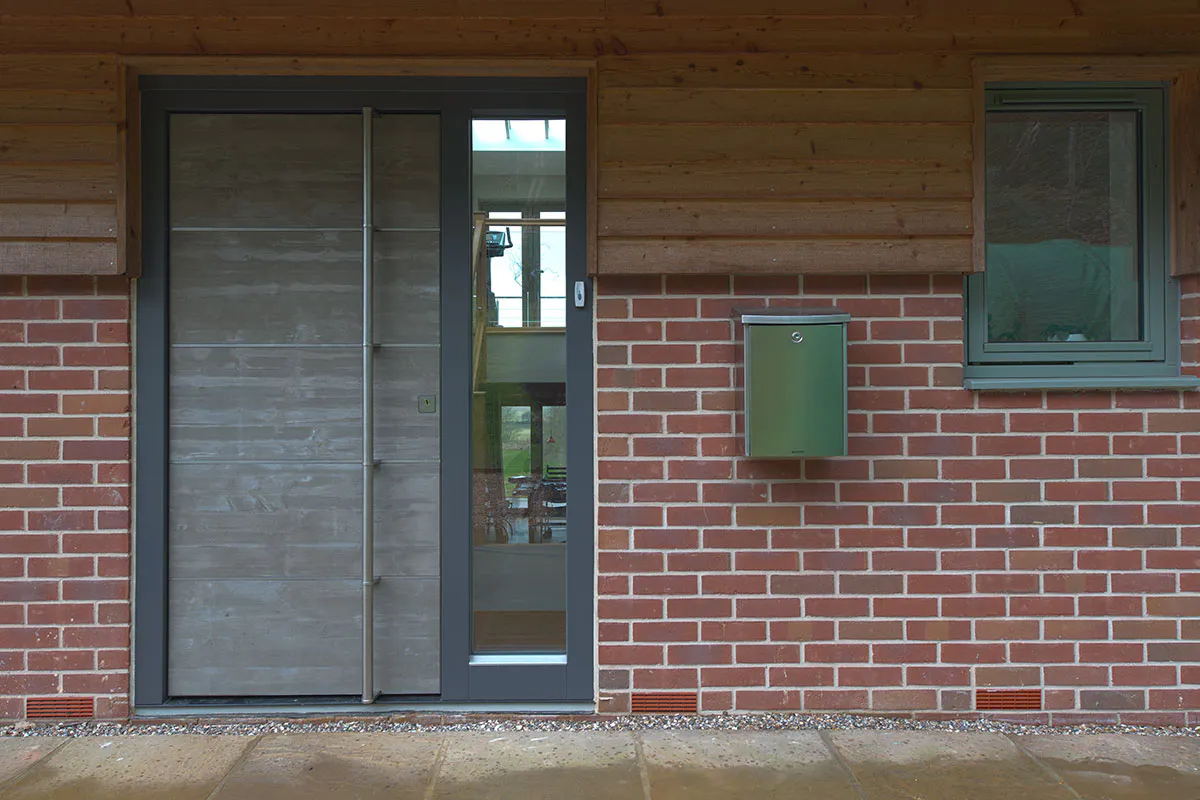 concrete look door with glazed side light and tall bar handle