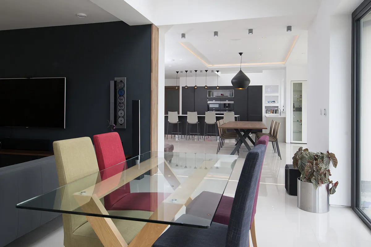 Modern open plan kitchen, dining and living space, well lit with large windows