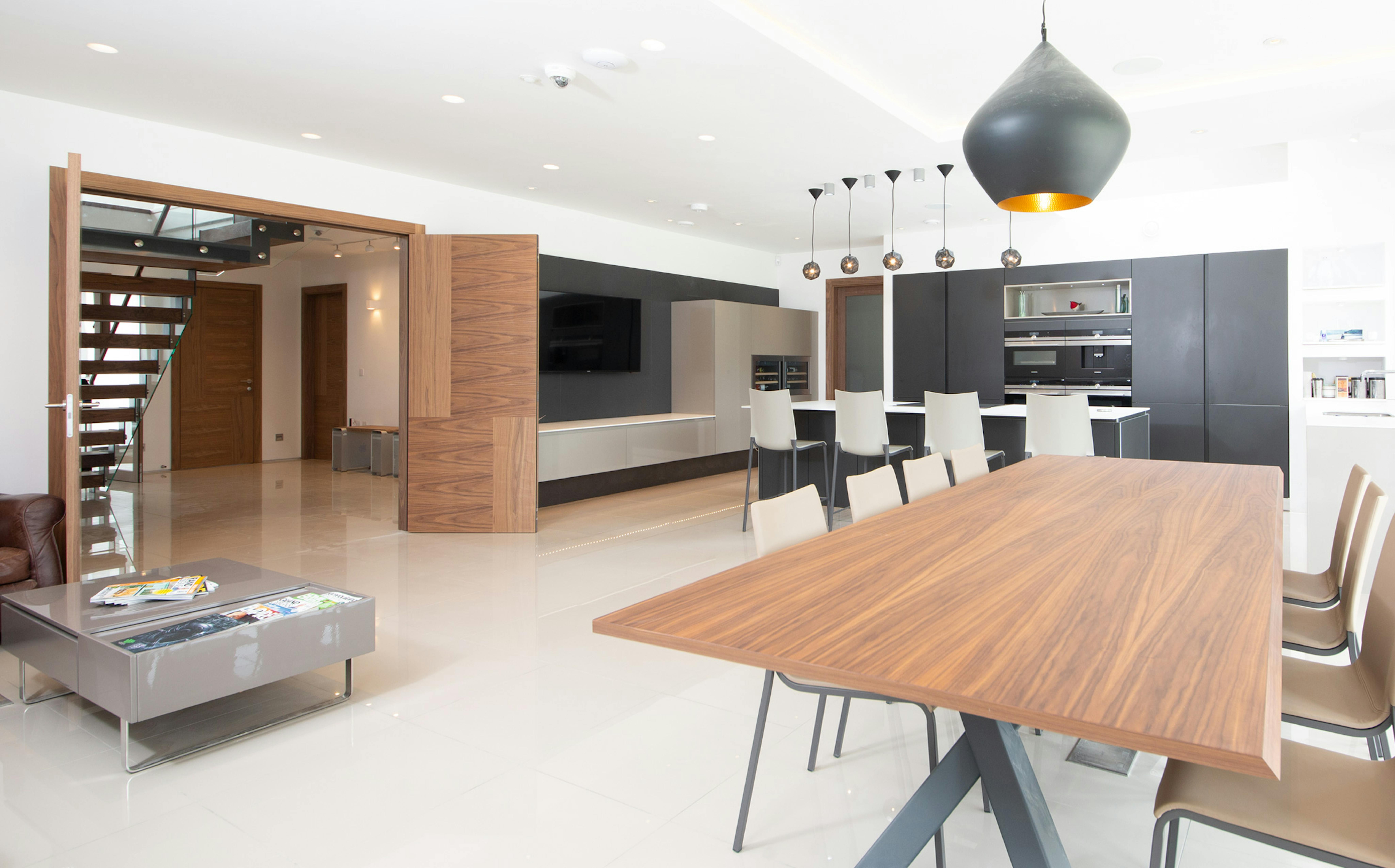 Large and modern open plan kitchen, dining and living area  featuring a Deuren double leaf door set - Vario 4 style, in a walnut veneer finish.