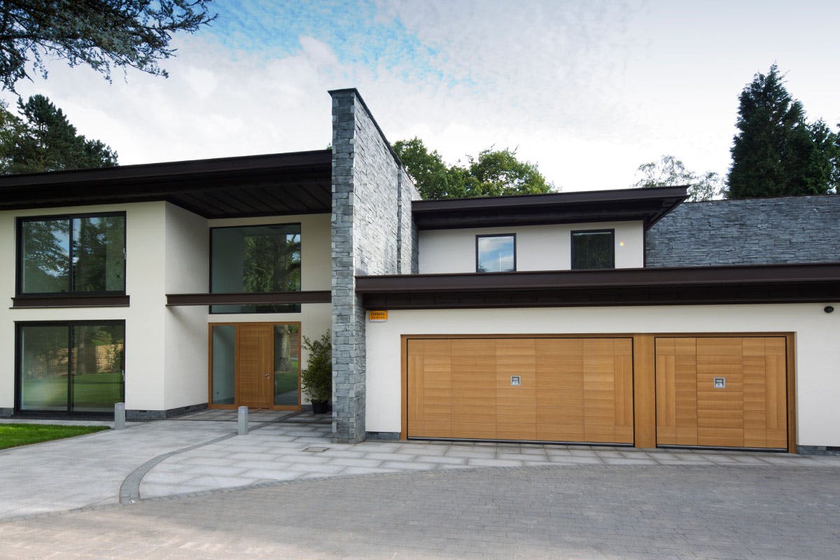 Luxury modern home with contemporary matching front and garage doors by Deuren - style is Versare in natural oak finish.