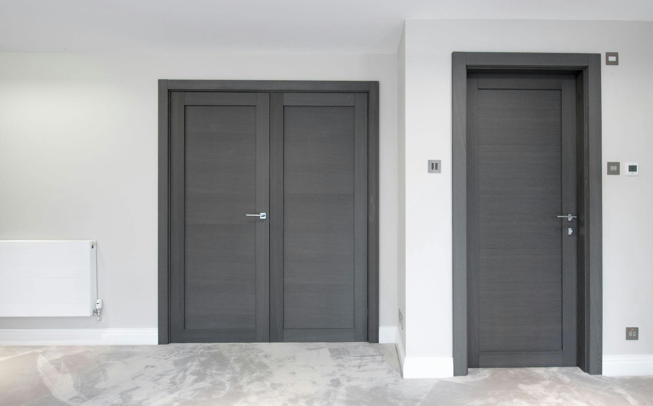 A contemporary living space featuring a single and double pre-hung door set, by Deuren-Gio style, finished in Grey Oak.