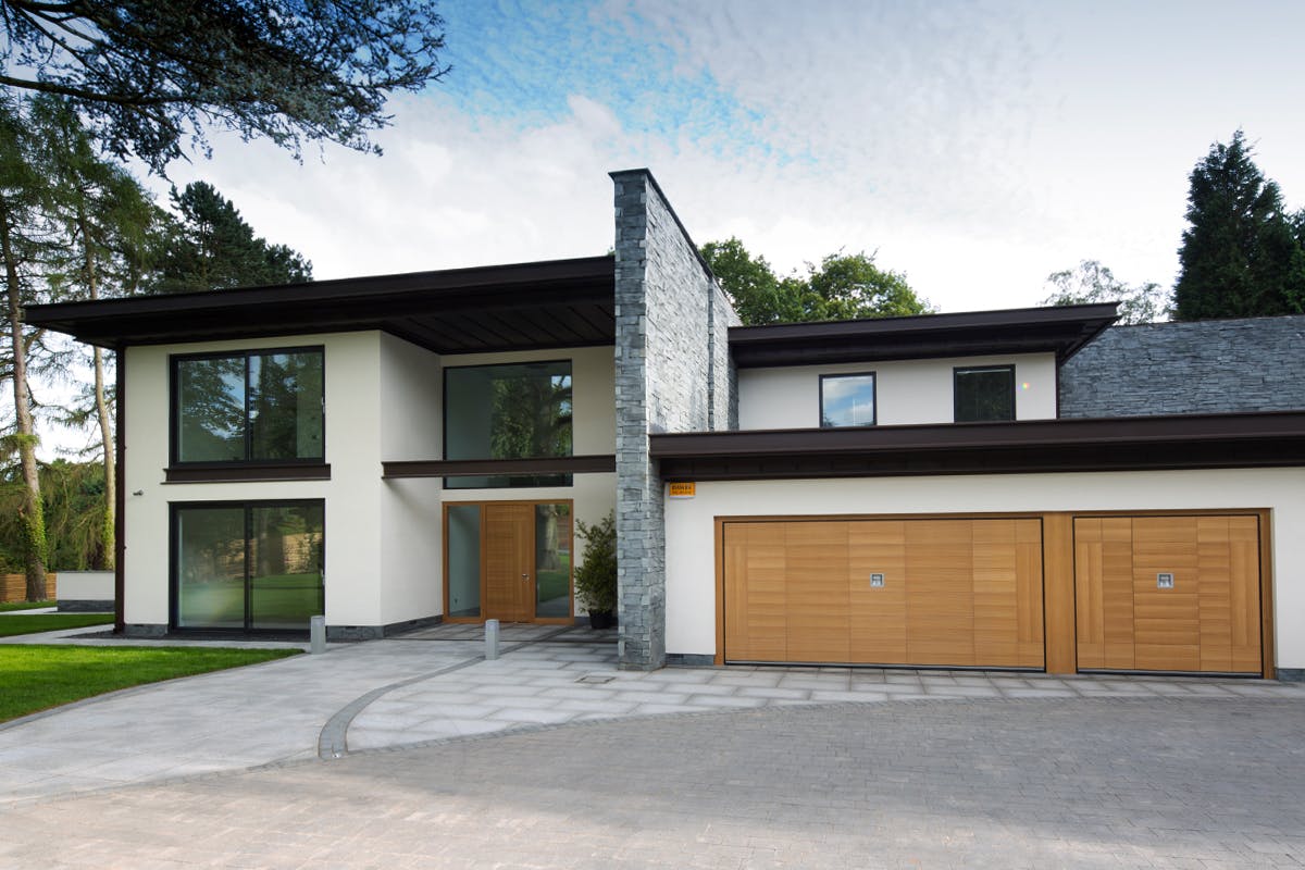 Ultra-contemporary home exterior with large expanses of glass and featuring matching front and garage doors by Deuren - Versare style in a natural oak finish.