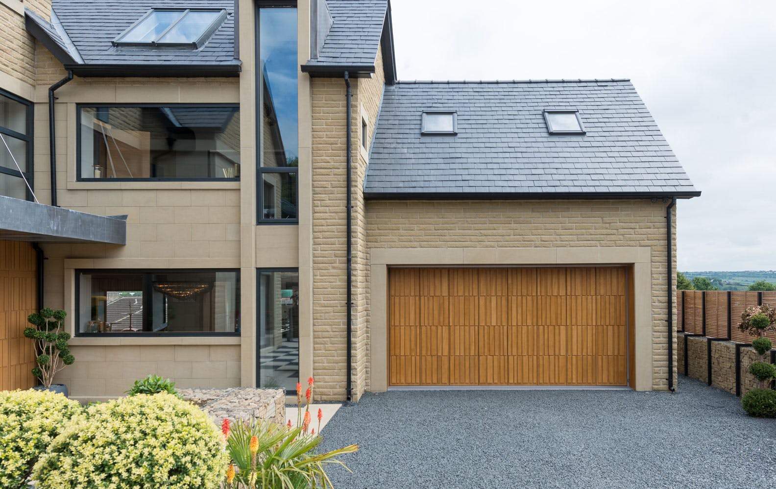 Large home exterior with matching contemporary front and garage doors by Deuren - style is Tavole in honey oak finish. 