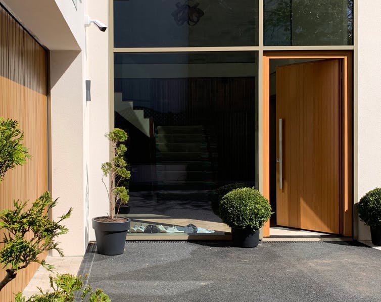 Modern large bespoke wooden front door surrounded by large windows