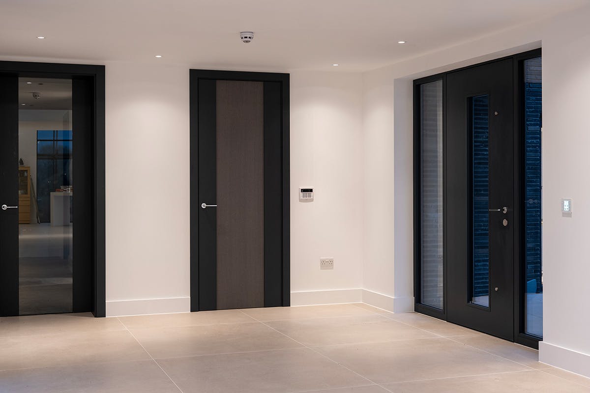 Contemporary hallway featuring Deuren made-to-measure internal and external doors - styles include Linea and Trem Glazed (interal) and Vista (external) with central glass panel and two side lights.