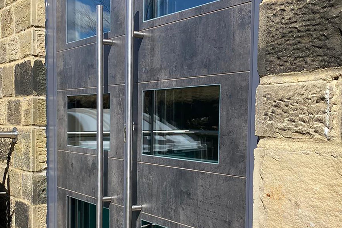 Industrial look double front door. Mid-grey concrete look finish with glass panels.
