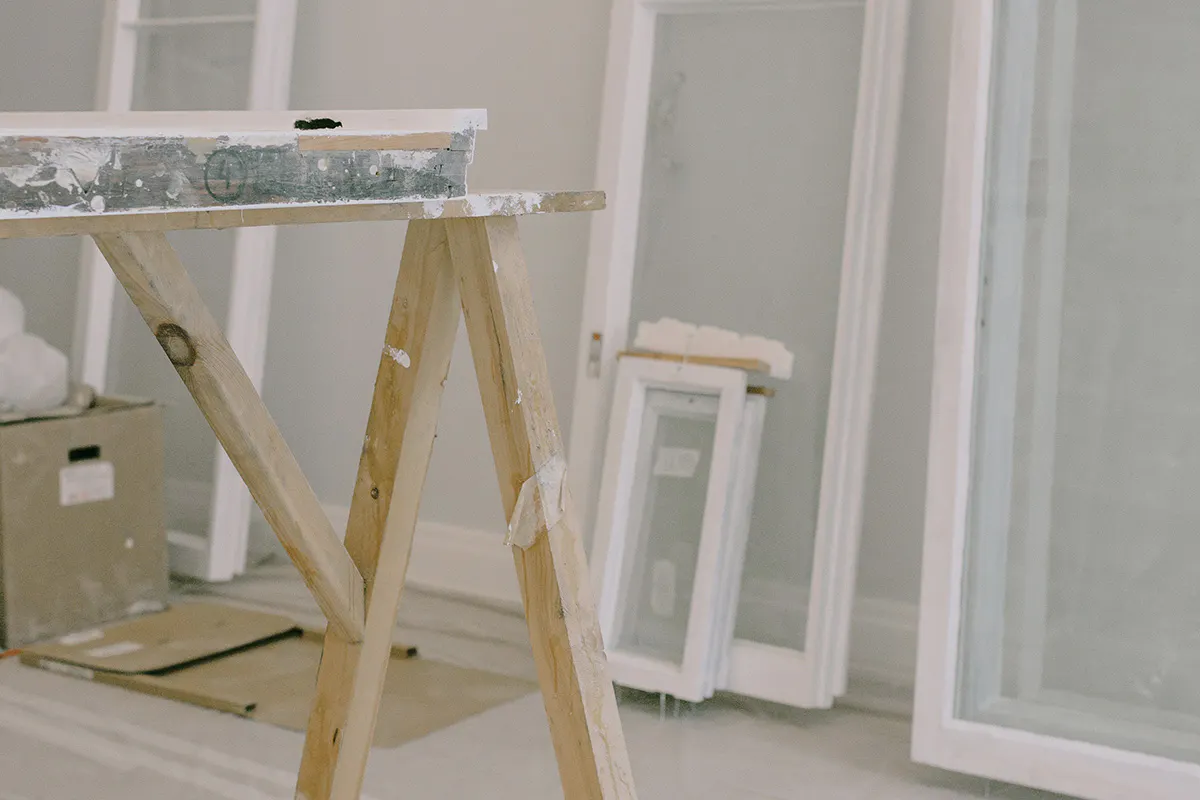 Window frames stood, leaning against a wall with a tiber trestle in the foreground