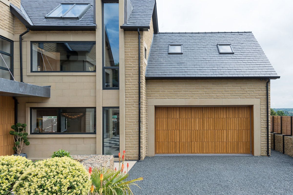 Large home exterior with matching contemporary front and garage doors by Deuren - style is Tavole in honey oak finish.